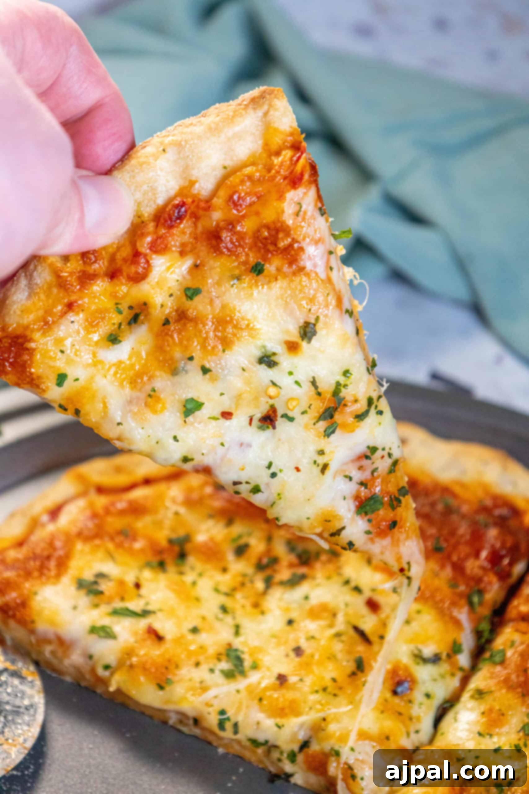 A hand reaching for a steaming slice of freshly baked homemade pizza, pulling it from the pan.