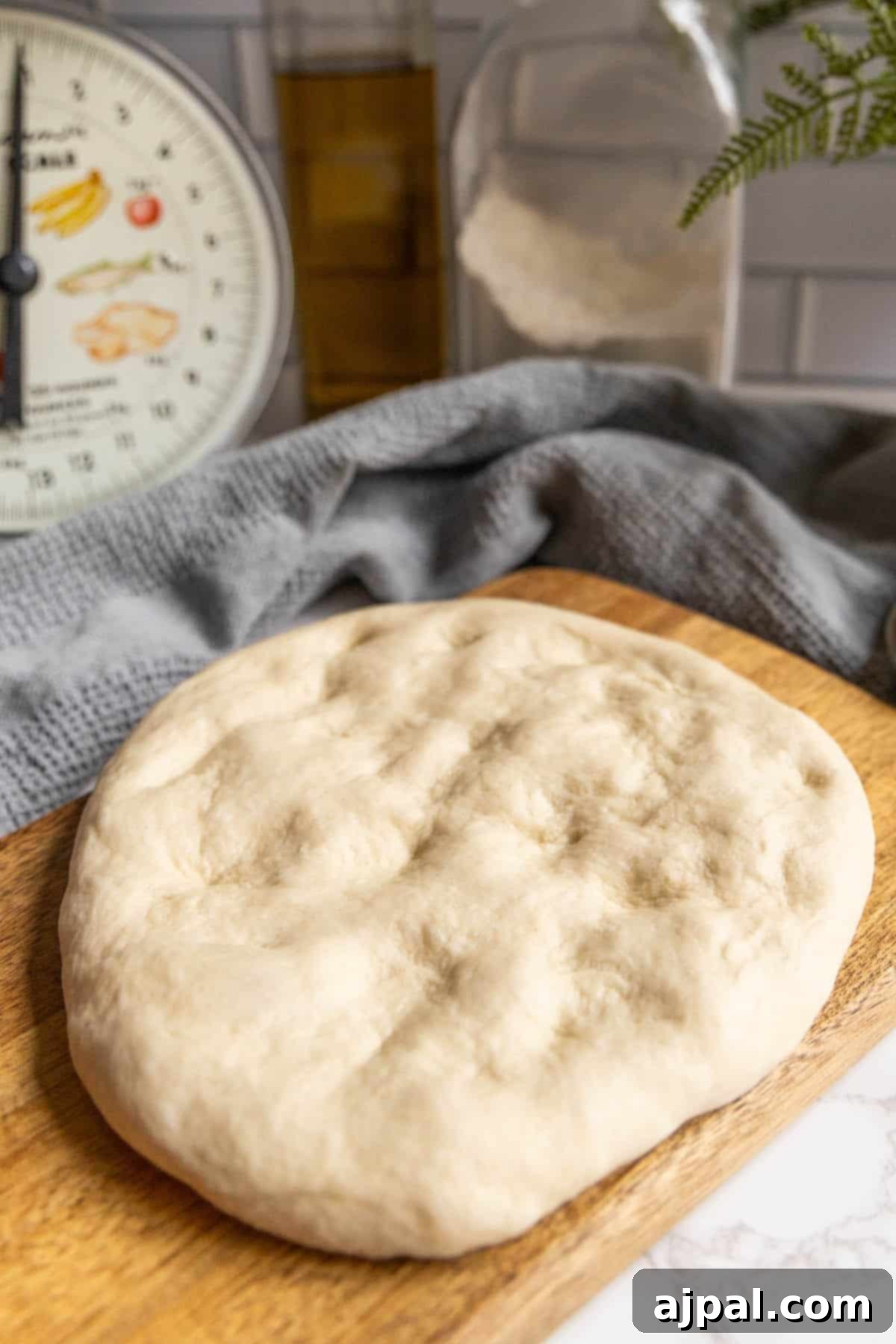 A perfectly rounded, homemade pizza dough resting on a rustic wooden cutting board.
