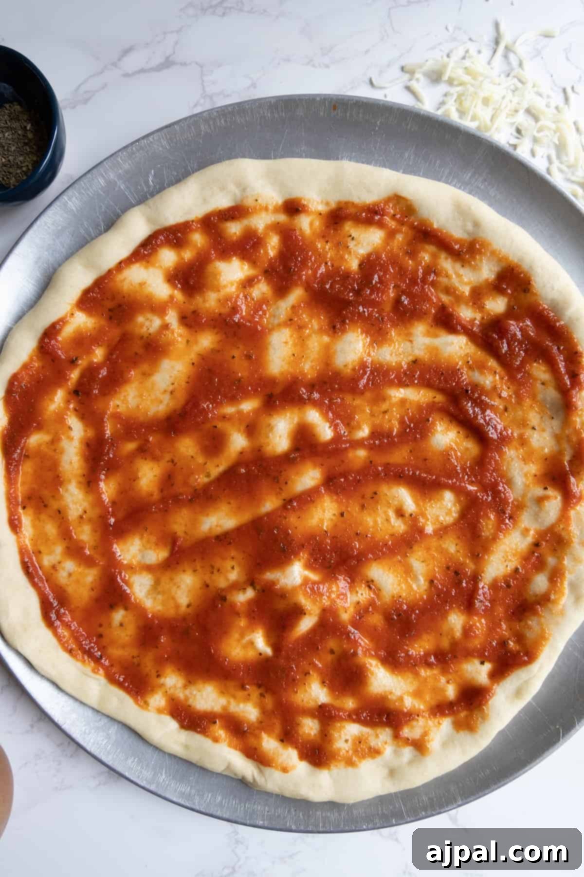 An easy homemade pizza in a pan with marinara sauce and cheese, preparing for the oven.
