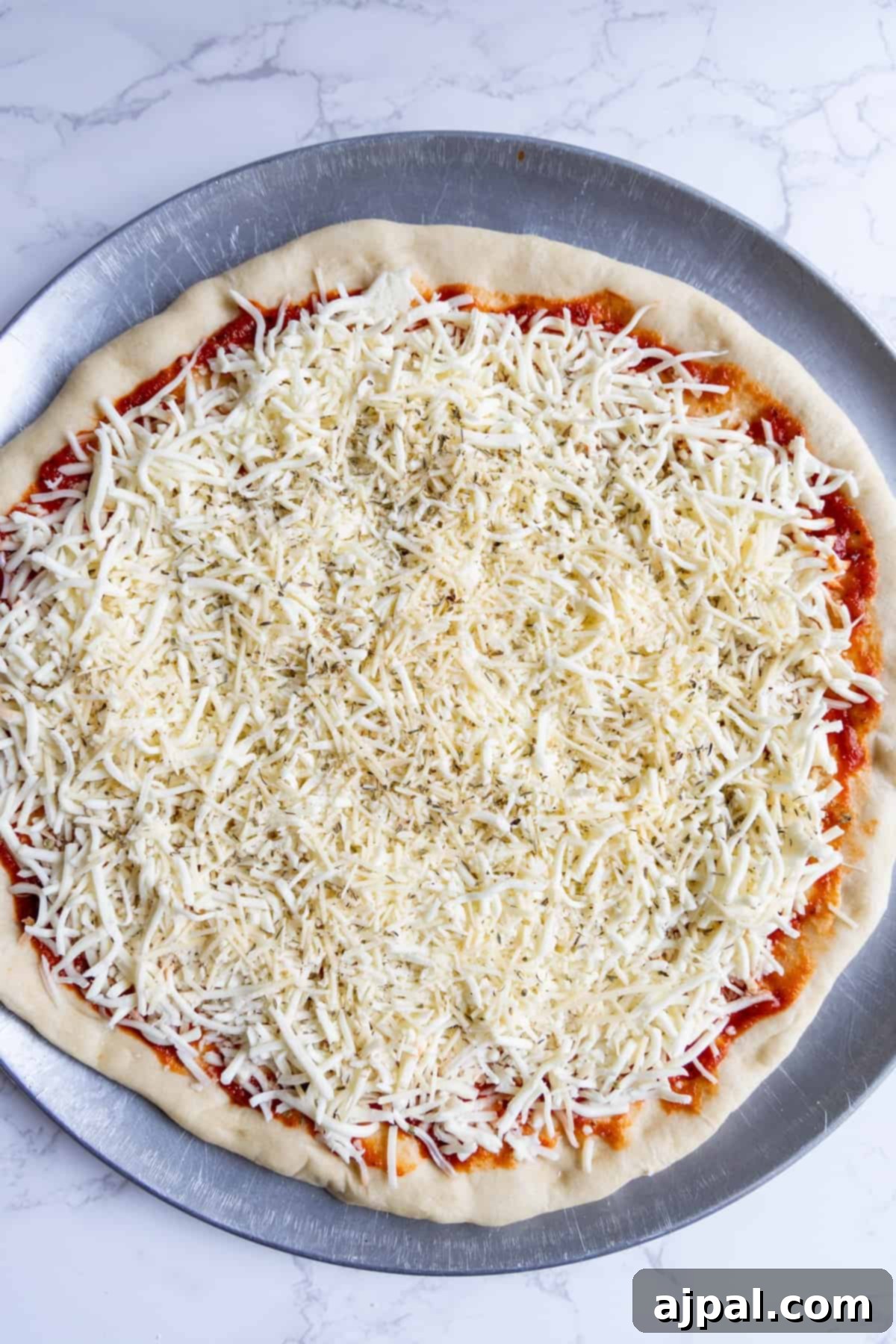 A freshly baked easy homemade pizza with golden cheese and sauce, still on the metal pan.