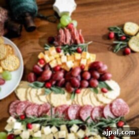A Christmas cheese board adorned with crackers and grapes on a table.