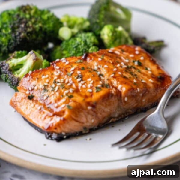 Korean BBQ Galbi Flanken Ribs 10 A plate with Japanese BBQ Salmon, glazed and topped with sesame seeds, served alongside roasted broccoli, with a fork placed on the side.