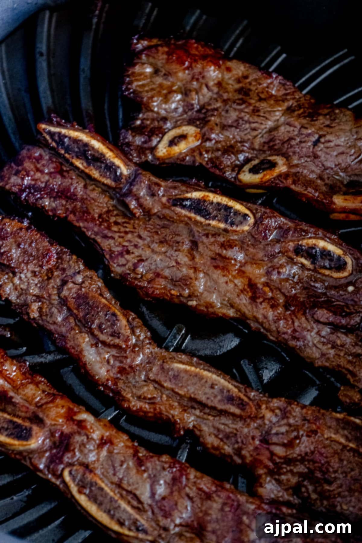 Korean BBQ Galbi Flanken Ribs 5 Flanken ribs sizzling and browning beautifully on a hot grill, flames dancing around the edges, creating a perfect char.