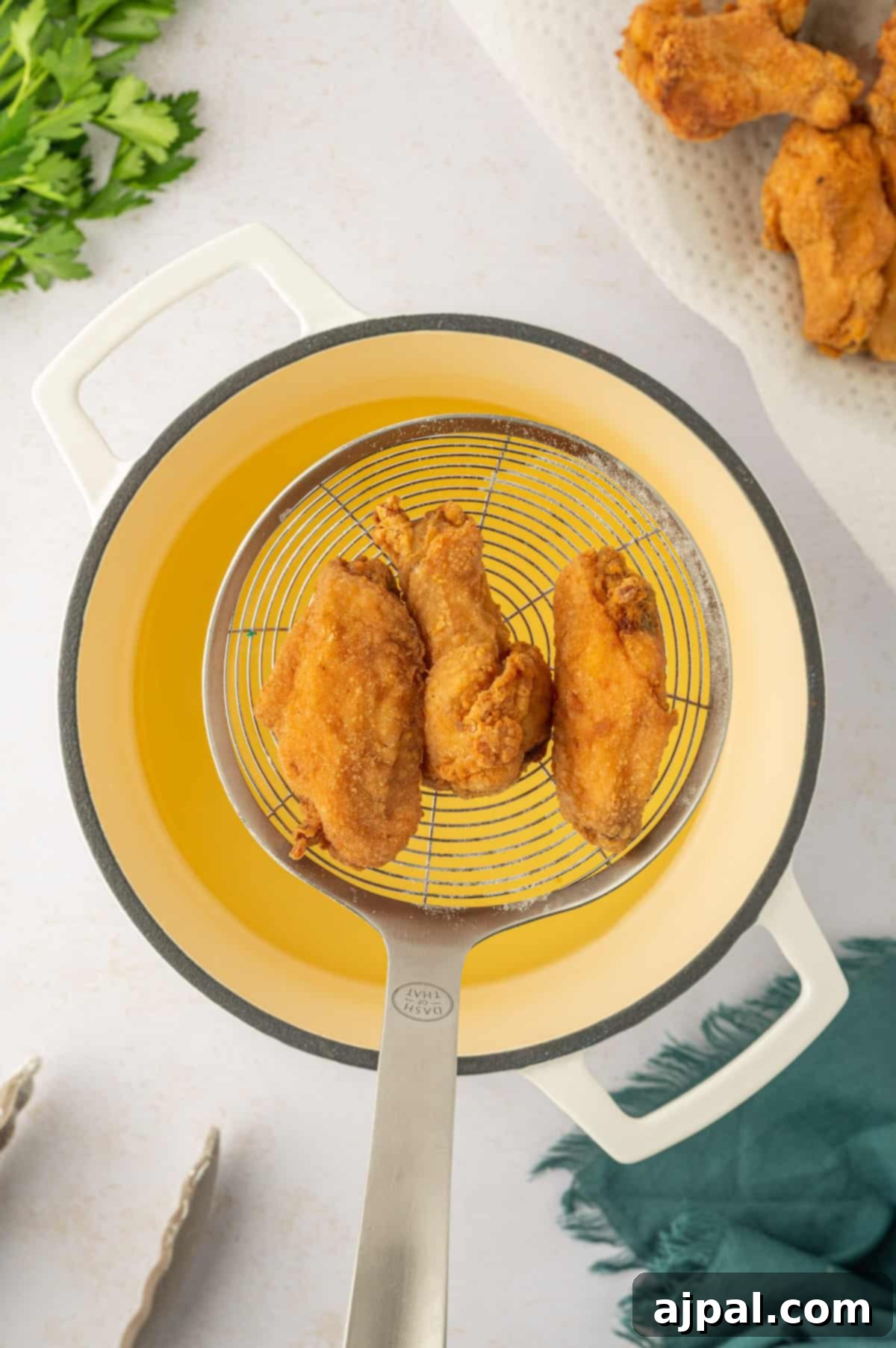 Crispy chicken wings being flipped in a pan, ensuring even cooking and a perfect golden hue.