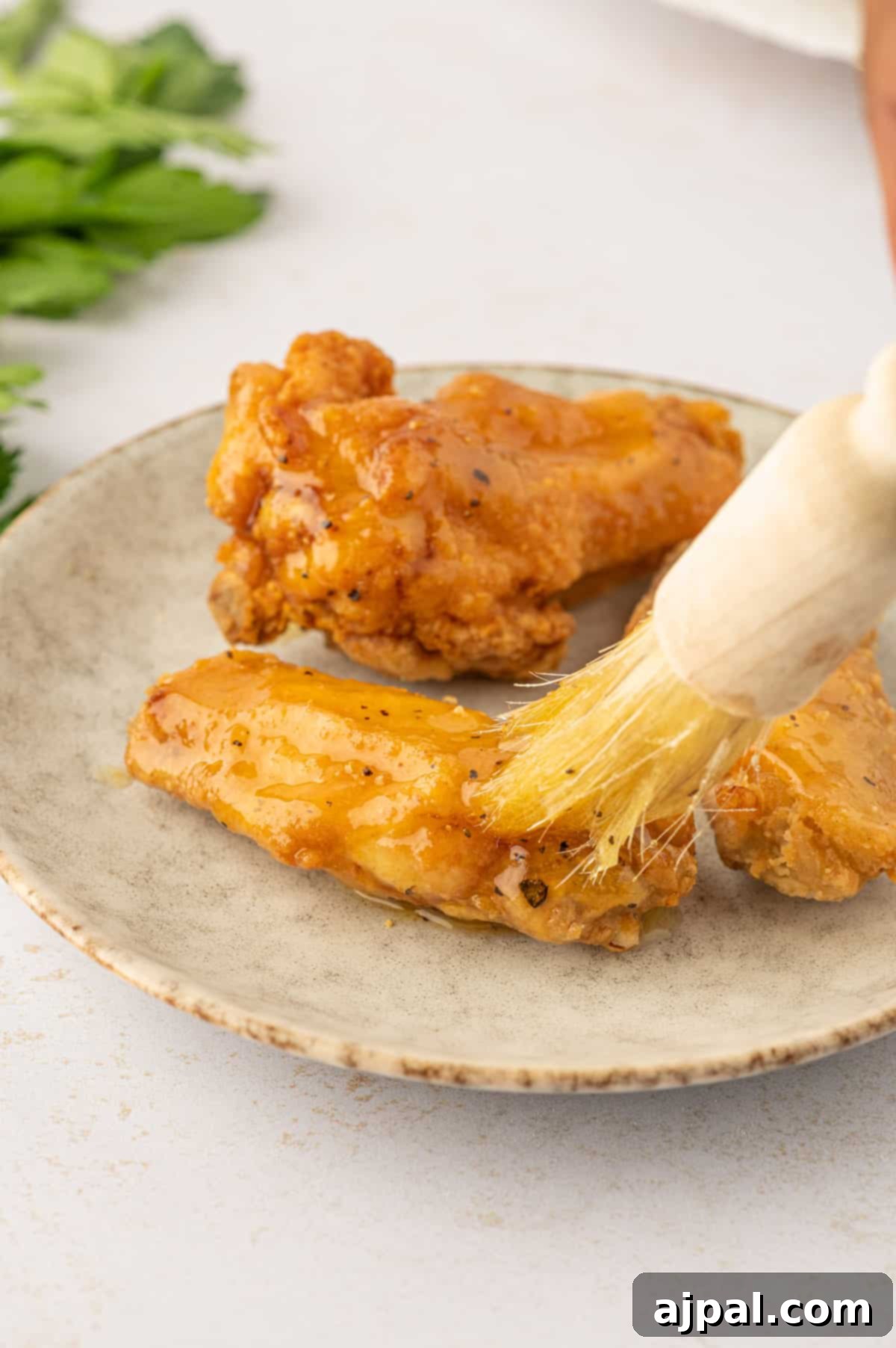 A hand dipping a crispy lemon pepper chicken wing into a creamy, savory sauce.