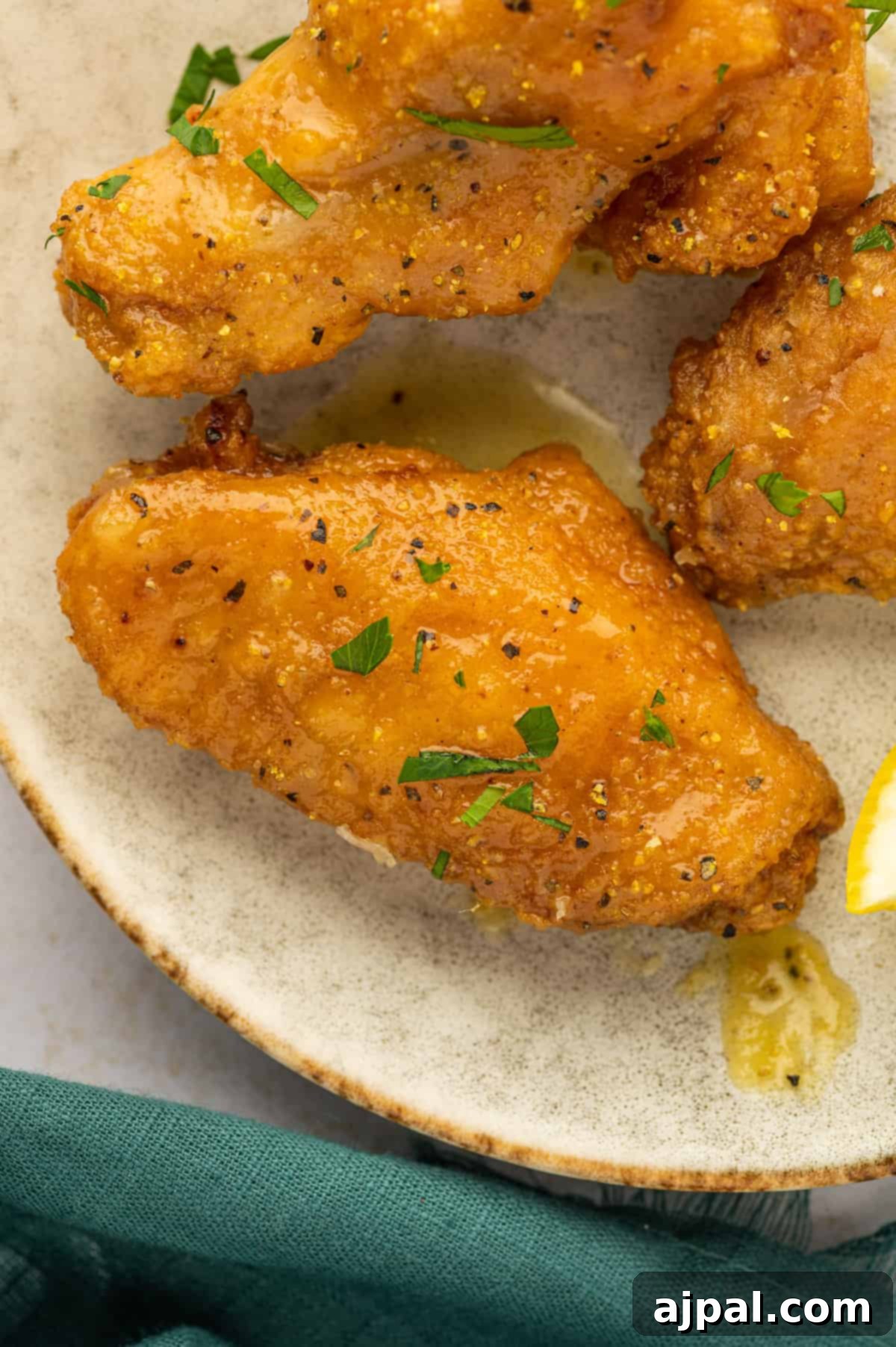 A plate of perfectly cooked lemon pepper chicken wings, adorned with a fresh lemon wedge, ready to be enjoyed.