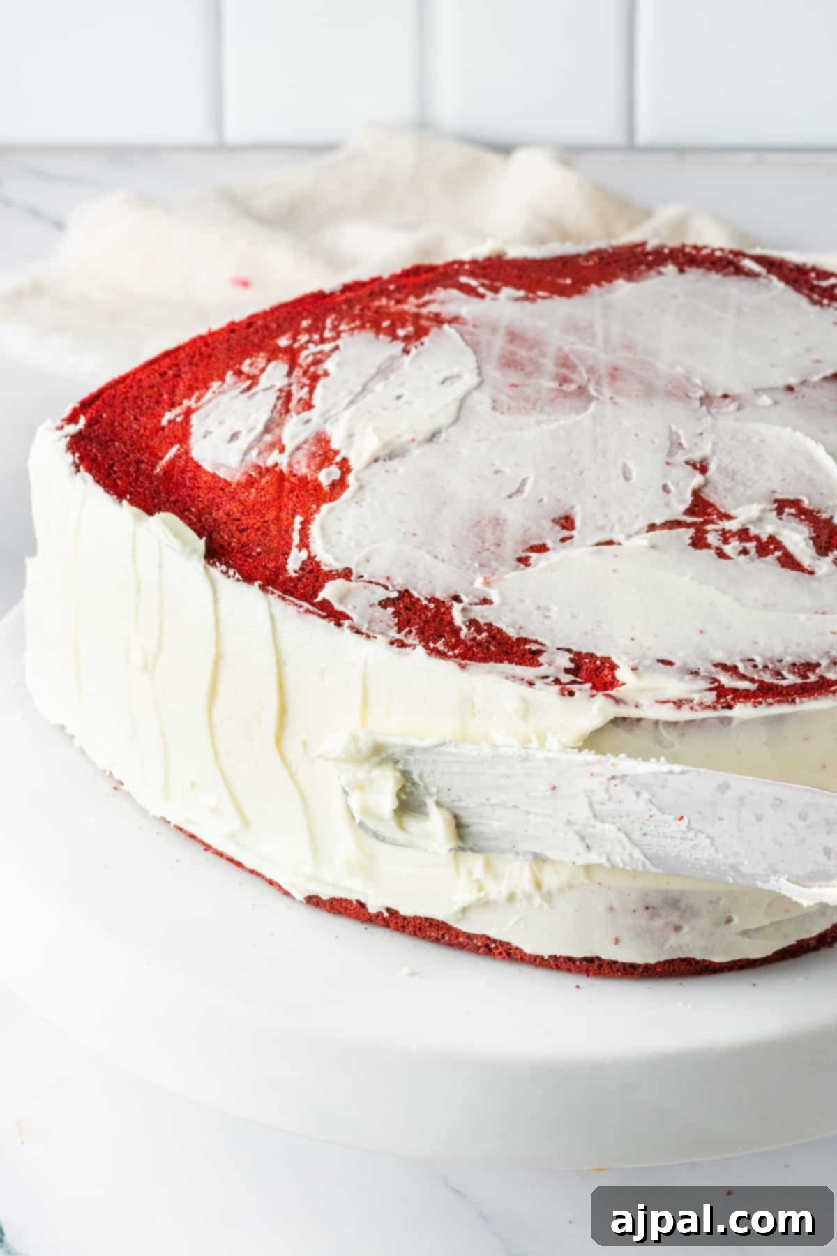 A mouthwatering Red Velvet Cake, perfectly frosted, is beautifully presented on a pristine white plate, promising a delightful treat.