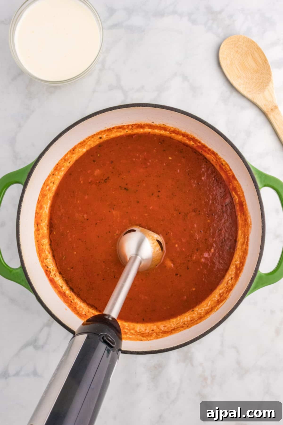 A pot of vibrant red tomato sauce, rich and flavorful, with a wooden spoon stirring it. Hint of red pepper adds a delicious kick.