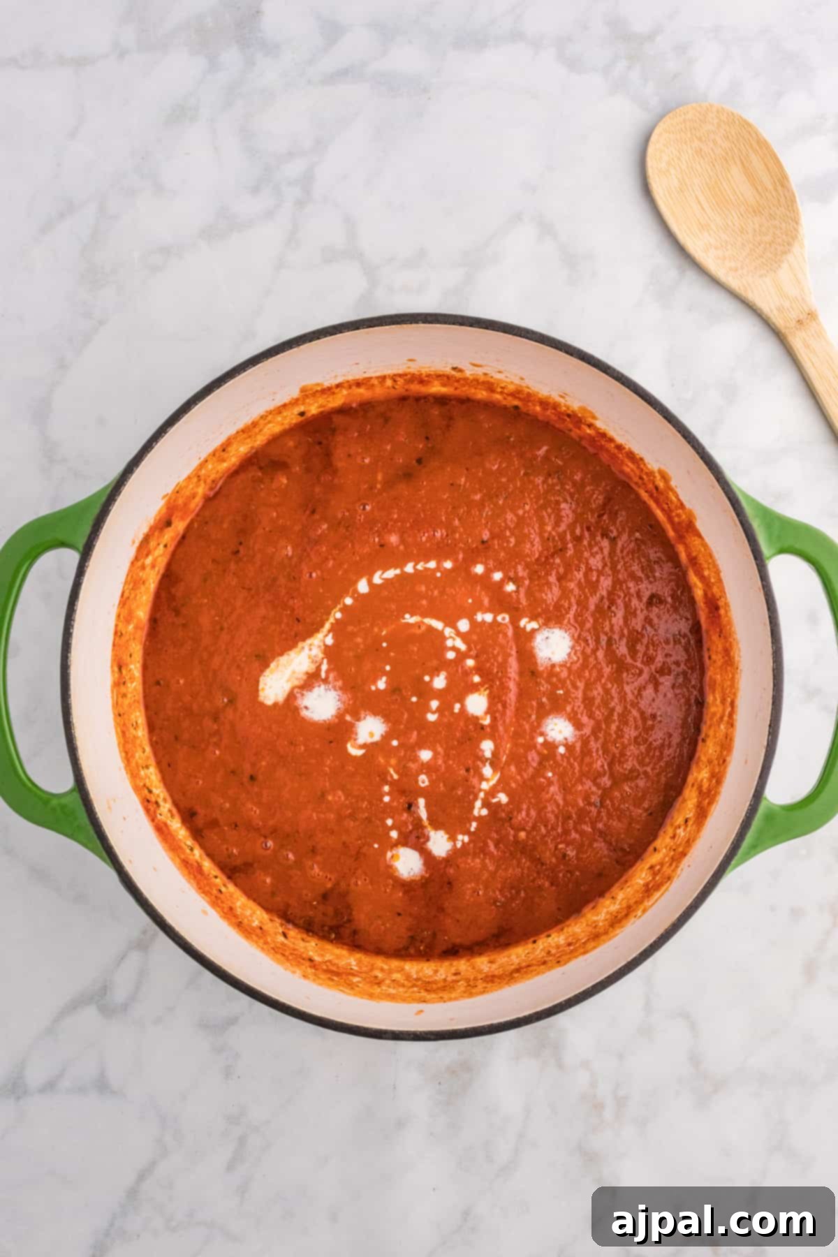 A pot of tomato sauce bubbling gently on the stovetop, releasing a fragrant steam, indicating it's nearly ready for the next step.