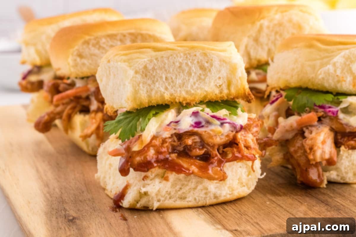 Smoky BBQ Chicken Minis 11 A top-down view of perfectly arranged BBQ pulled chicken sliders on a rustic wooden cutting board, ready for a party.