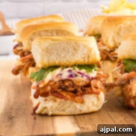 Smoky BBQ Chicken Minis 14 BBQ pulled chicken sliders on a cutting board, ready to be enjoyed.