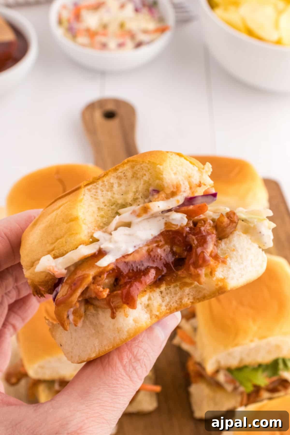 Smoky BBQ Chicken Minis 4 Delicious BBQ pulled chicken sliders with coleslaw on a cutting board, ready to be served.