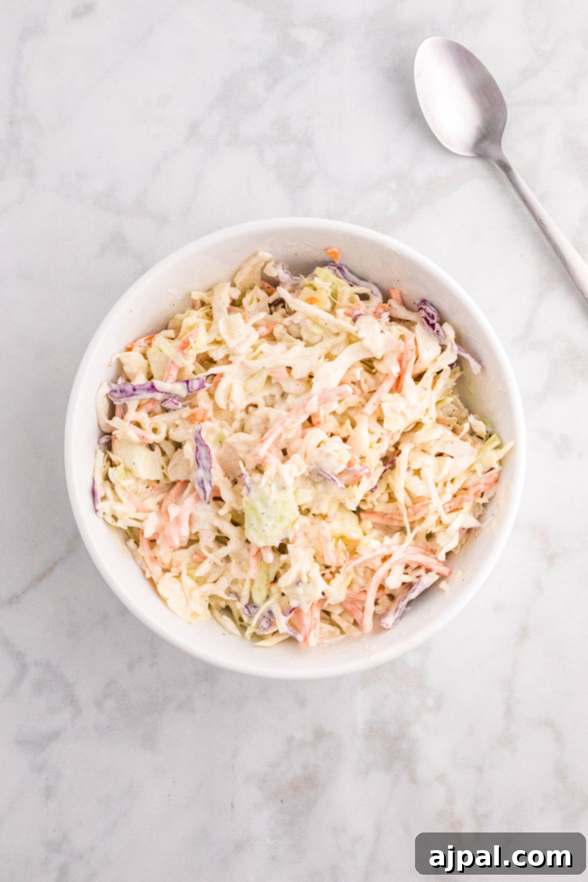 Smoky BBQ Chicken Minis 5 Fresh, creamy coleslaw in a white bowl with a serving spoon, prepared to accompany BBQ chicken sliders.
