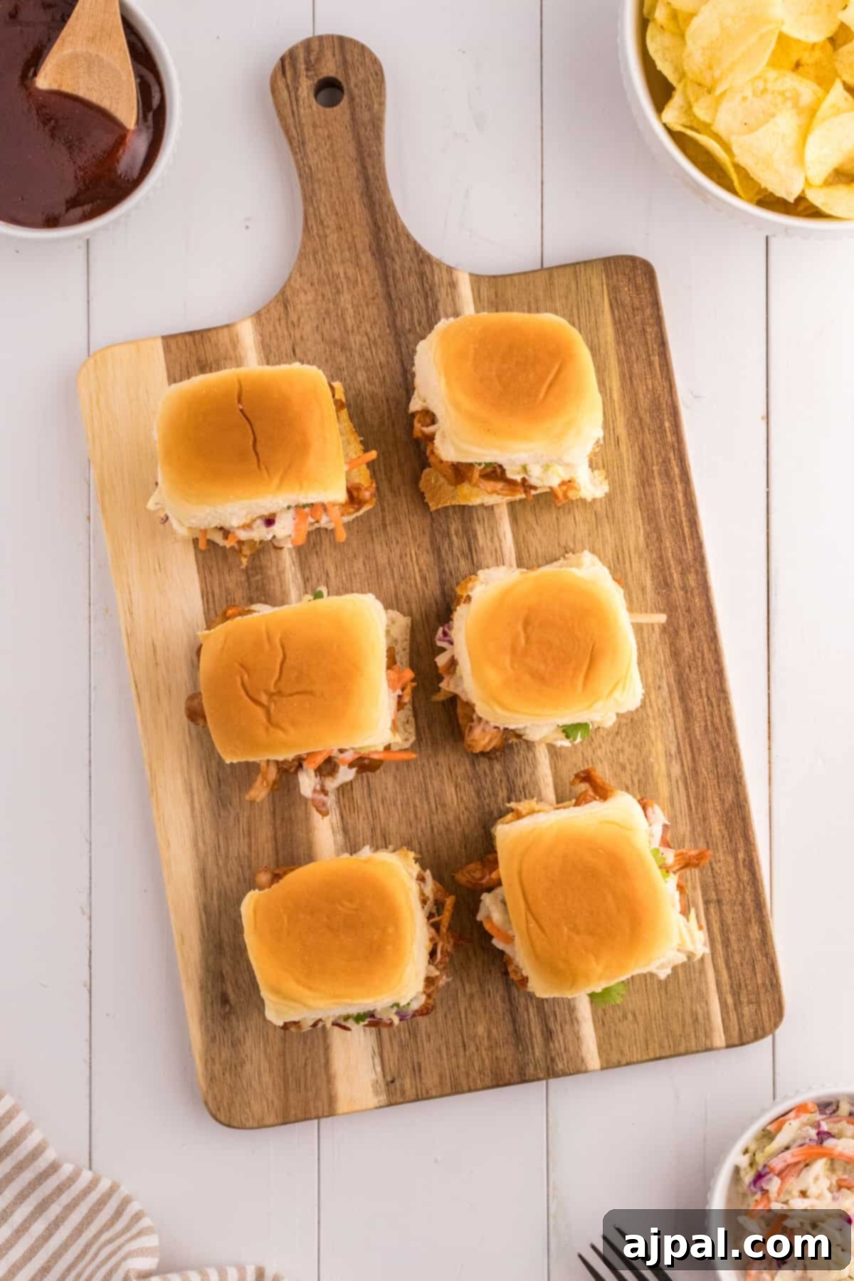 Smoky BBQ Chicken Minis 9 Overhead view of homemade BBQ pulled chicken sliders on a rustic wooden cutting board, garnished with fresh cilantro.