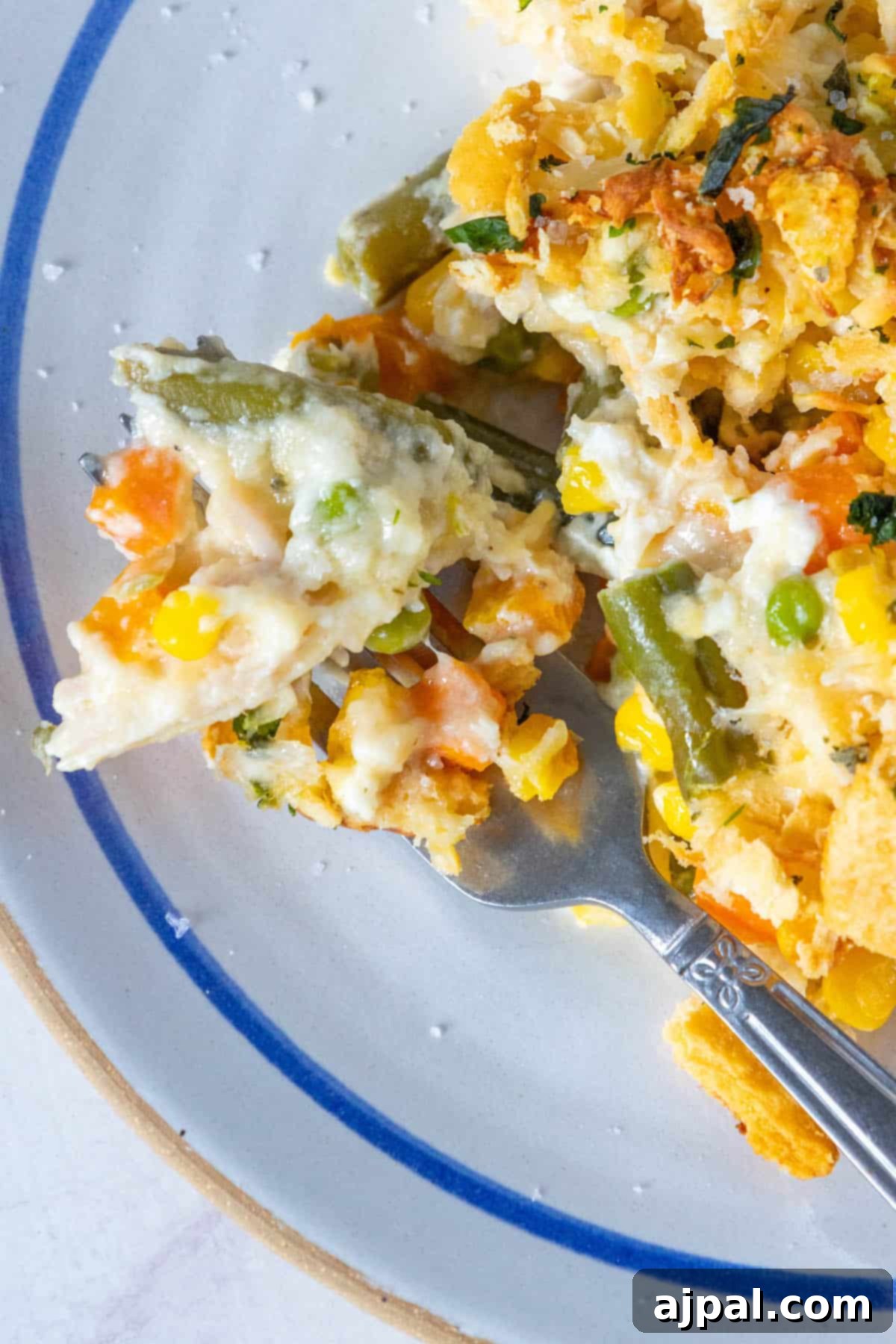 A plate of creamy chicken and vegetable casserole with a fork.