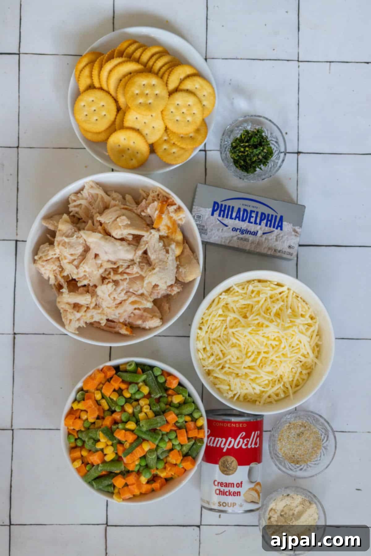 The creamy and vegetable-filled ingredients for a chicken pot pie are laid out on a tiled floor.