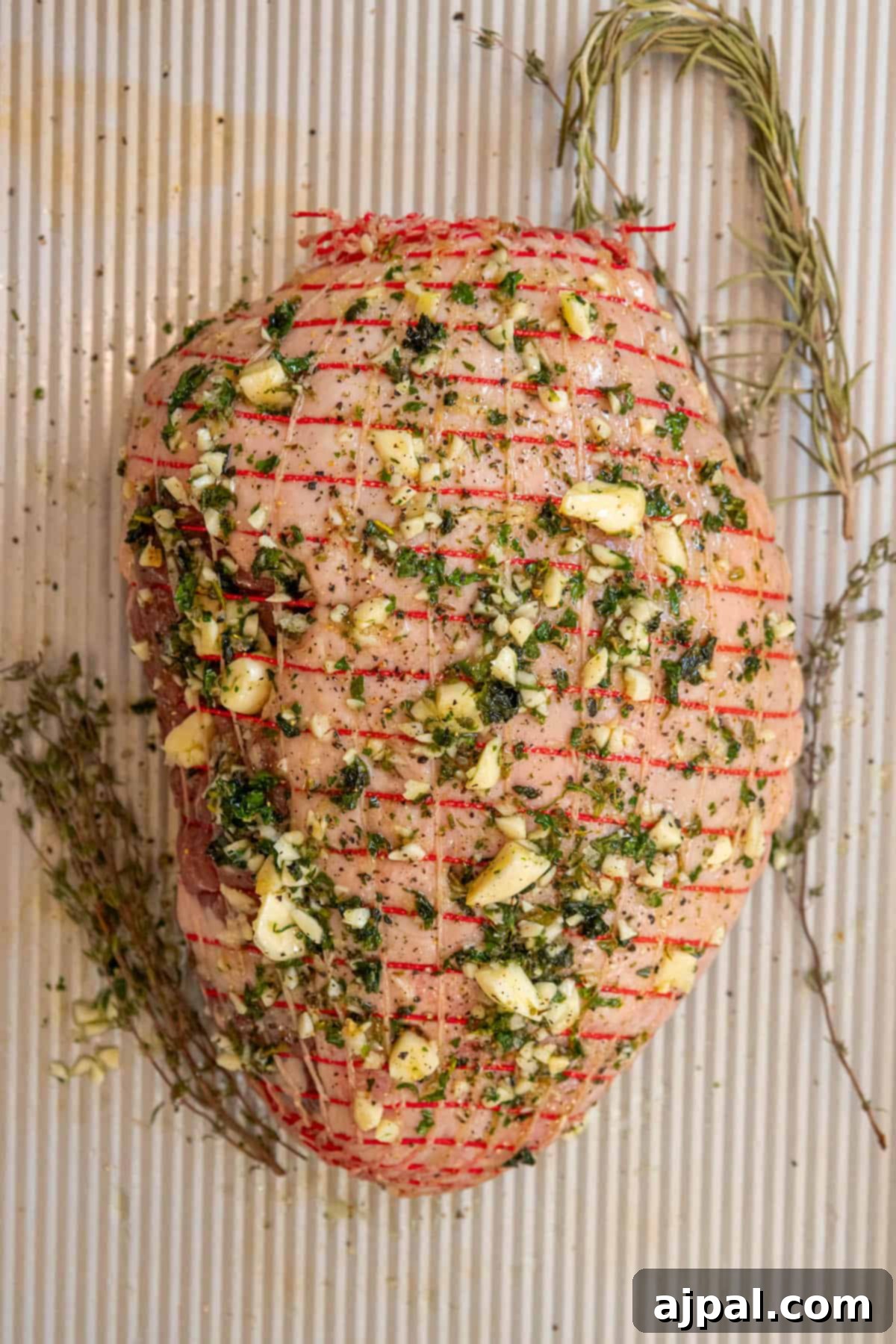 Succulent Reverse Seared Lamb Leg 6 A close-up view of the herb and spice-crusted leg of lamb on a baking sheet, showcasing the rich texture before cooking.