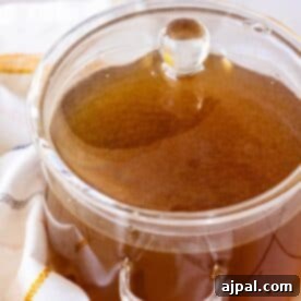 A homemade pot of brown chicken stock sitting on a towel.