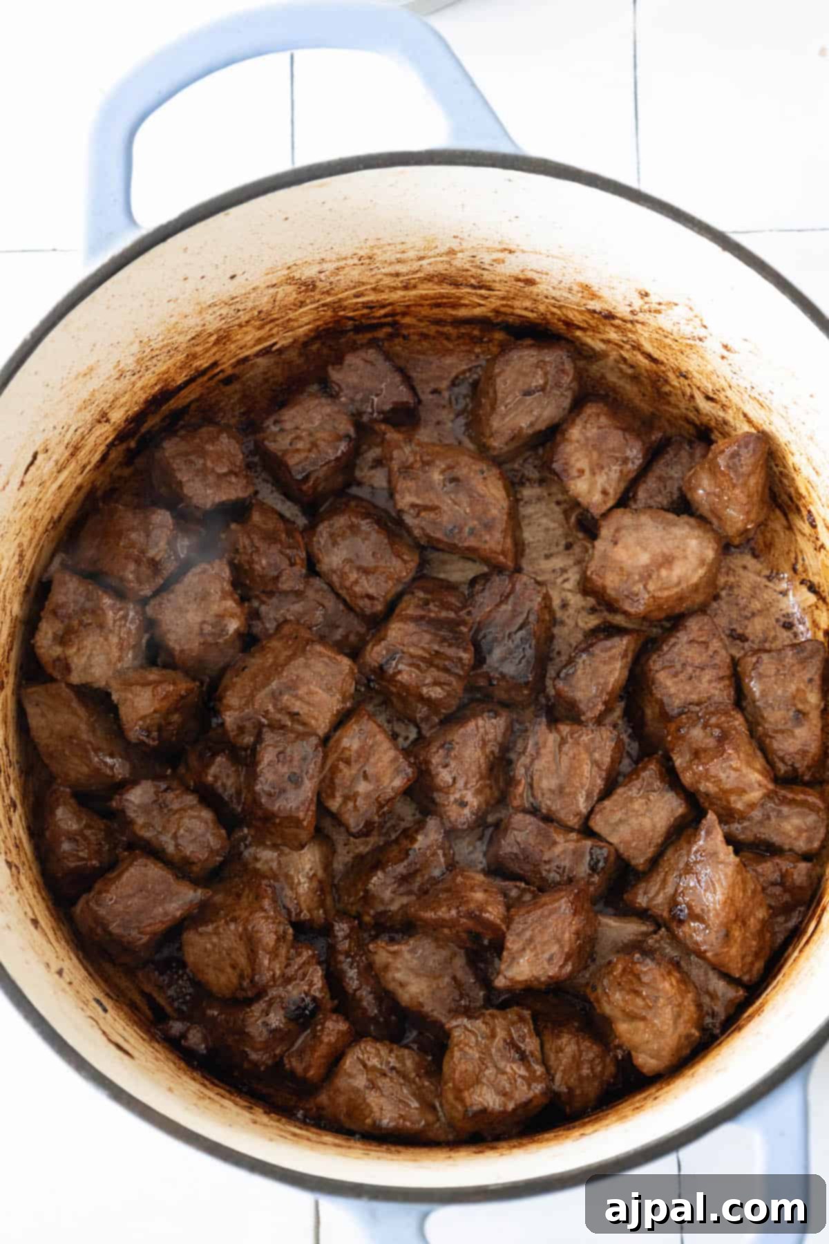A spicy beef stew simmering in a large pot on a tiled kitchen surface, radiating warmth and flavor.