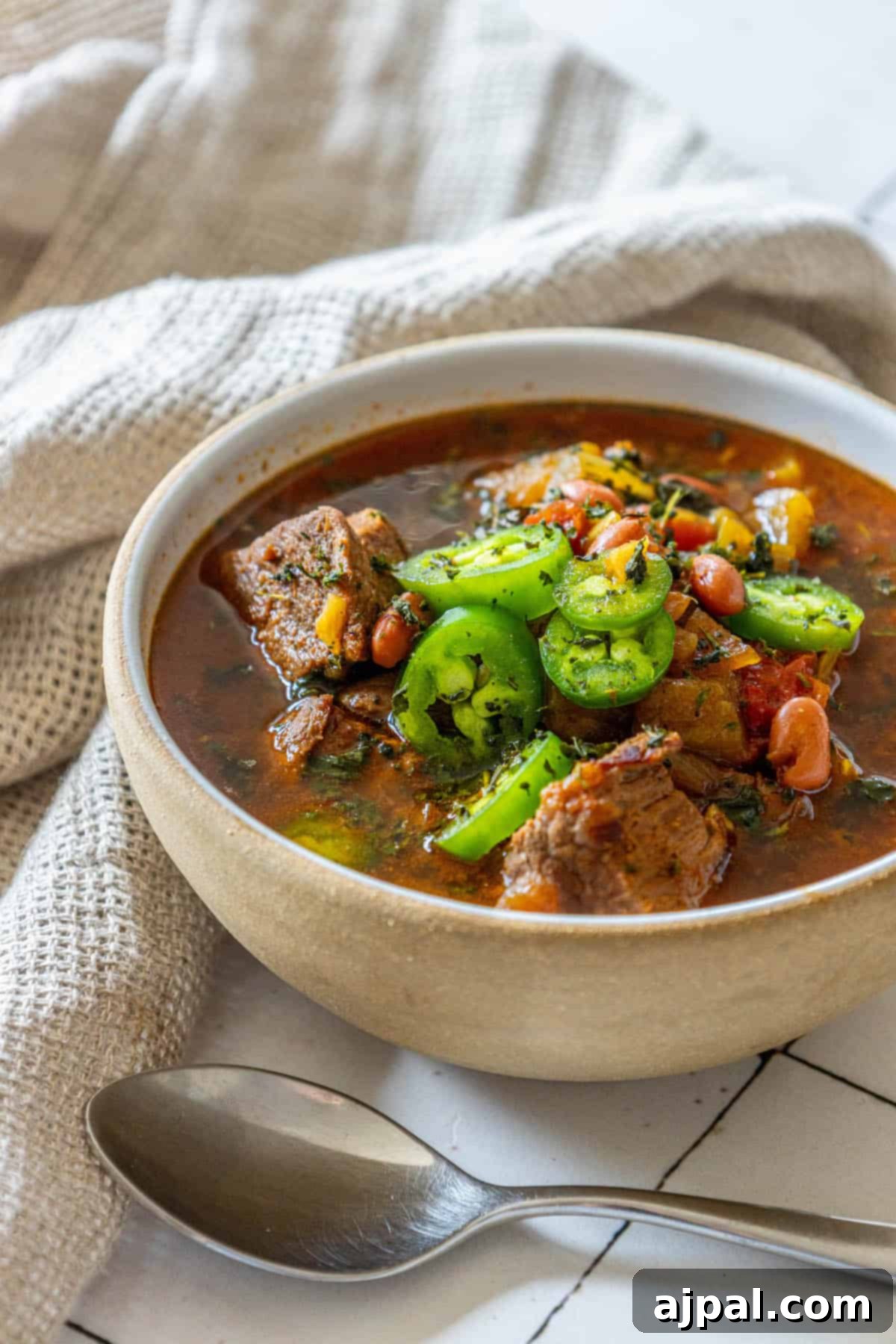 A generously sized bowl of rich beef soup, filled with tender chunks of meat and a medley of vegetables.