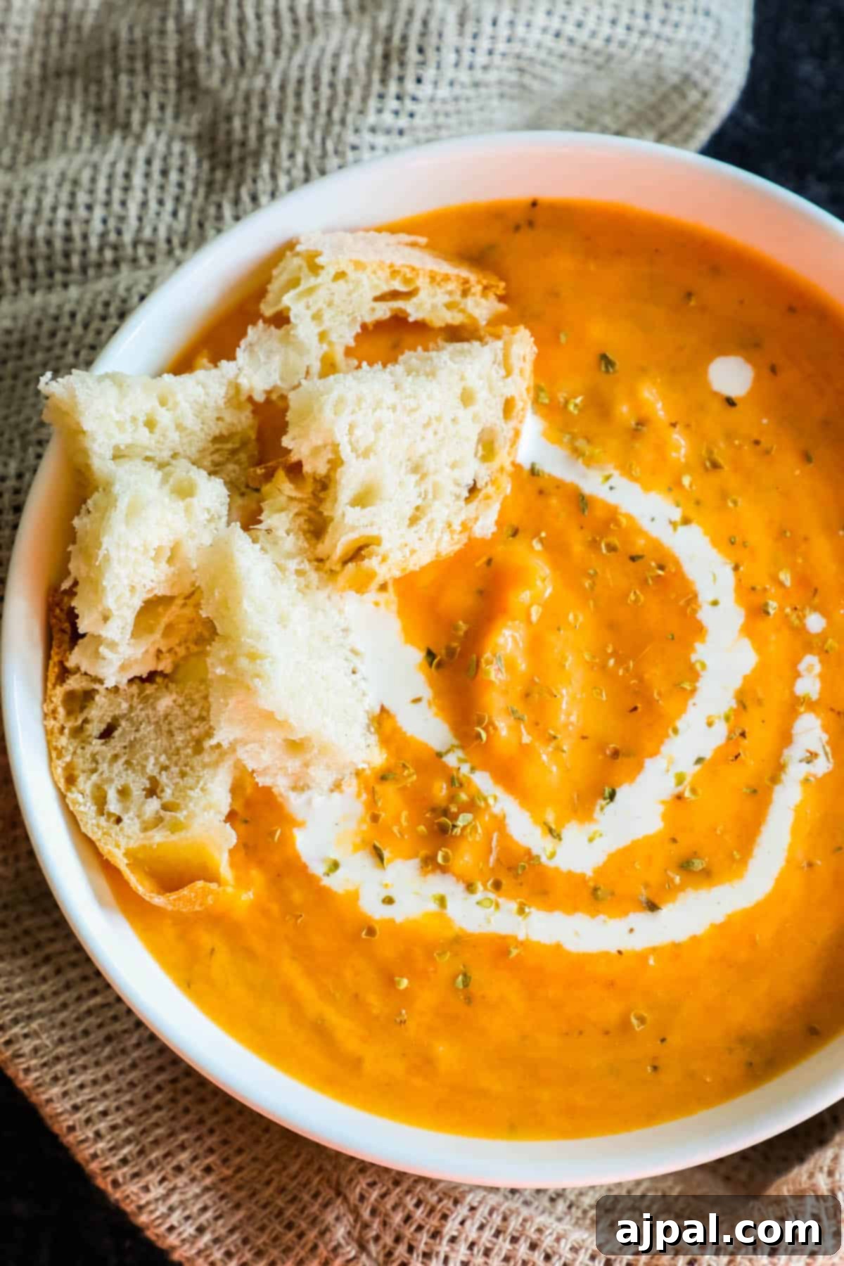 Hearty Roasted Tomato Soup 2 A steaming bowl of creamy roasted tomato soup, garnished with fresh herbs and served with golden croutons and a dollop of sour cream, showcasing its rich texture and inviting warmth.