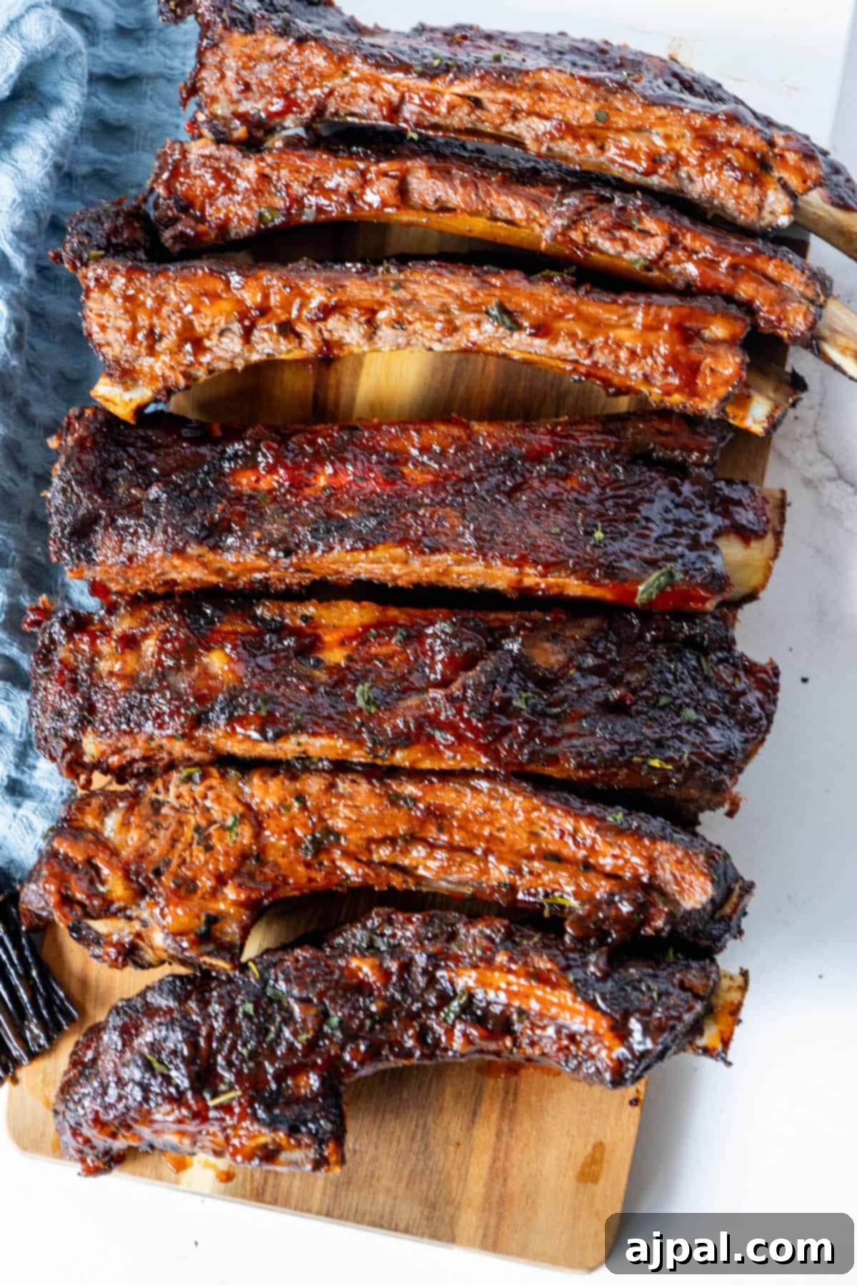 A large platter of perfectly cooked oven-baked beef ribs on a rustic wooden board, ready to be served and enjoyed by all.