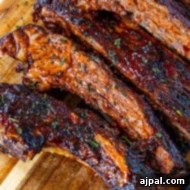 Oven-baked beef ribs on a wooden cutting board, ready for a delicious meal.