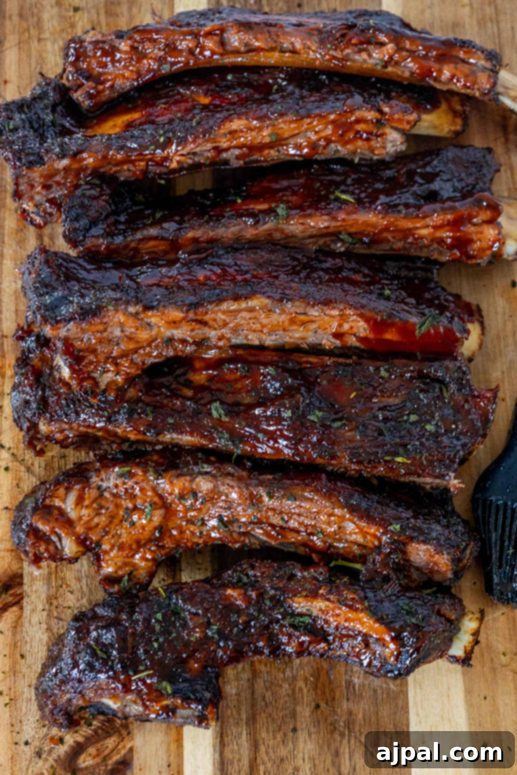 Close-up of succulent oven baked BBQ beef ribs on a wooden board, coated in a rich, caramelized sauce, highlighting their irresistible glaze.