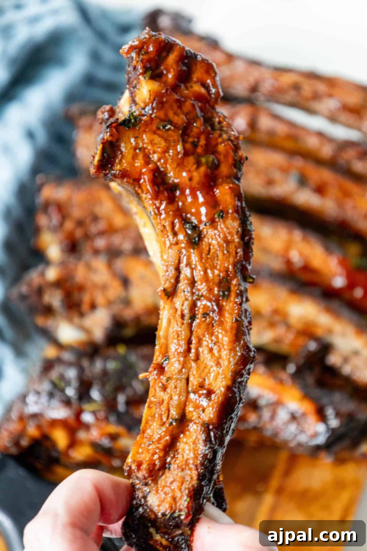 Perfectly baked BBQ beef ribs, glistening with rich sauce, on a wooden cutting board, ready to be served and enjoyed.