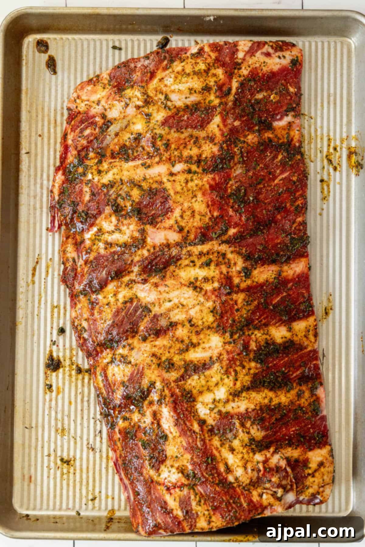 A full rack of tender oven-baked beef ribs, still on the baking sheet, showing their rich color and delicious texture.