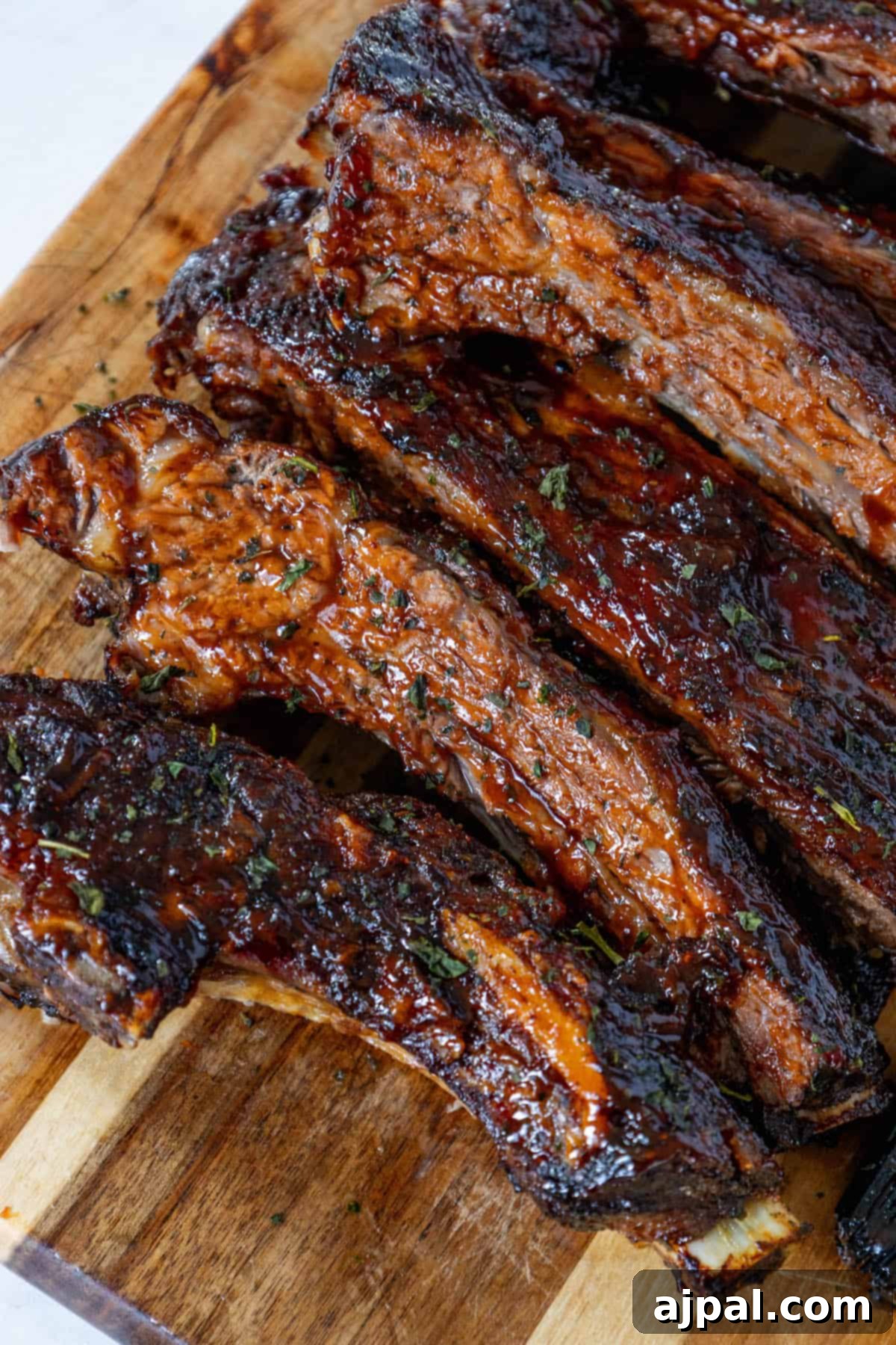 Perfectly baked BBQ beef ribs on a wooden cutting board, glistening with sauce and ready for a delicious meal.