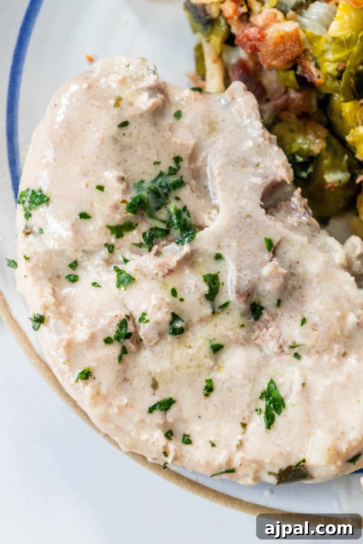 Slow Cooker Creamy Ranch Pork Chops 2 Crock Pot Pork Chops served with vegetables on a white plate, highlighting the creamy ranch sauce.
