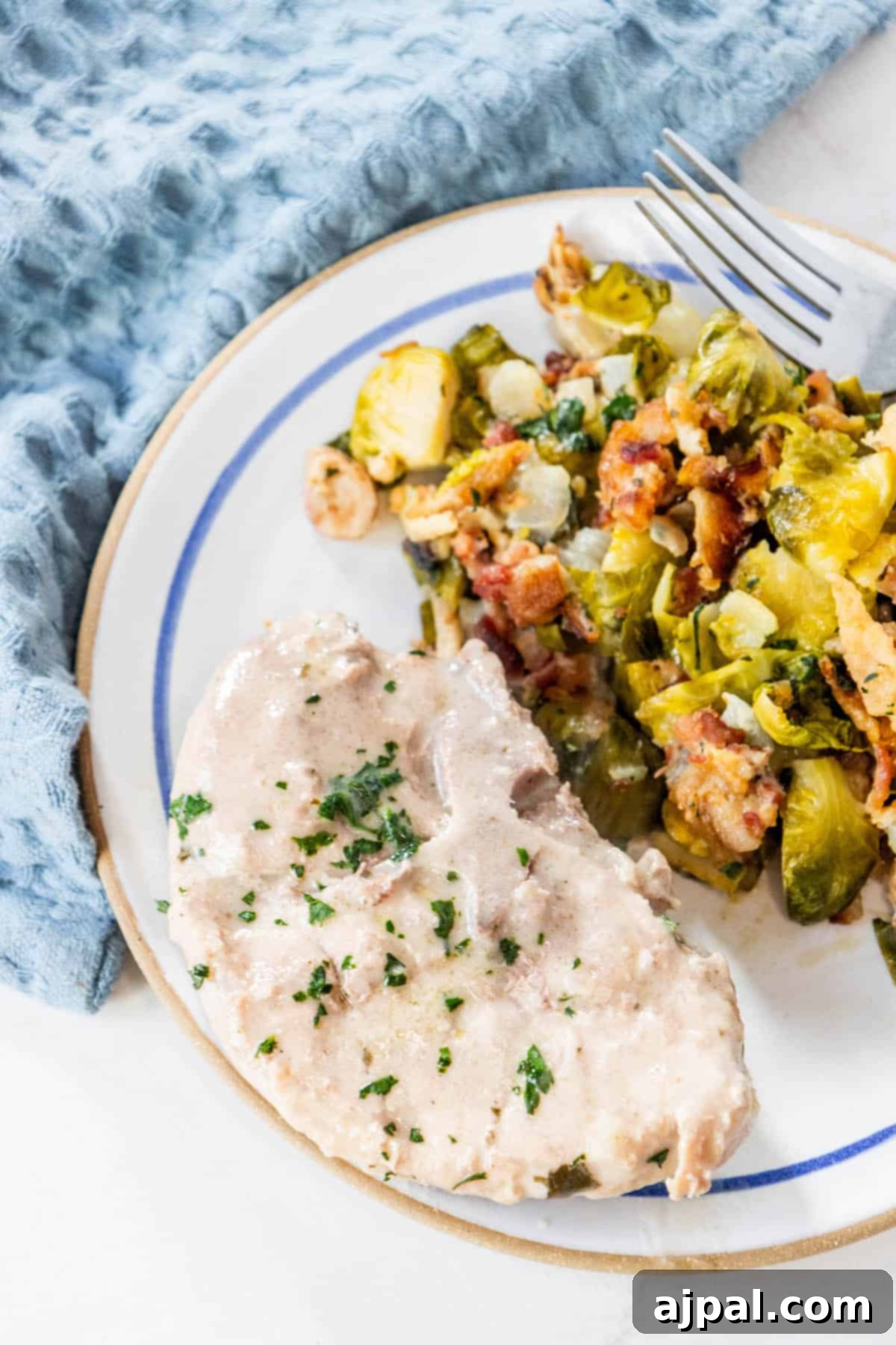 Slow Cooker Creamy Ranch Pork Chops 11 A creamy plate with chicken and brussels sprouts on it, garnished with fresh herbs.