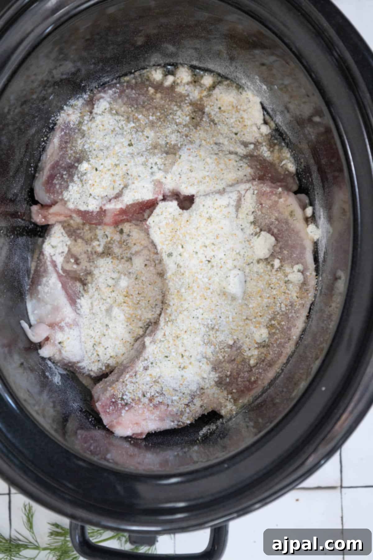 Slow Cooker Creamy Ranch Pork Chops 6 A creamy crock pot filled with meat and seasonings, ready for slow cooking.