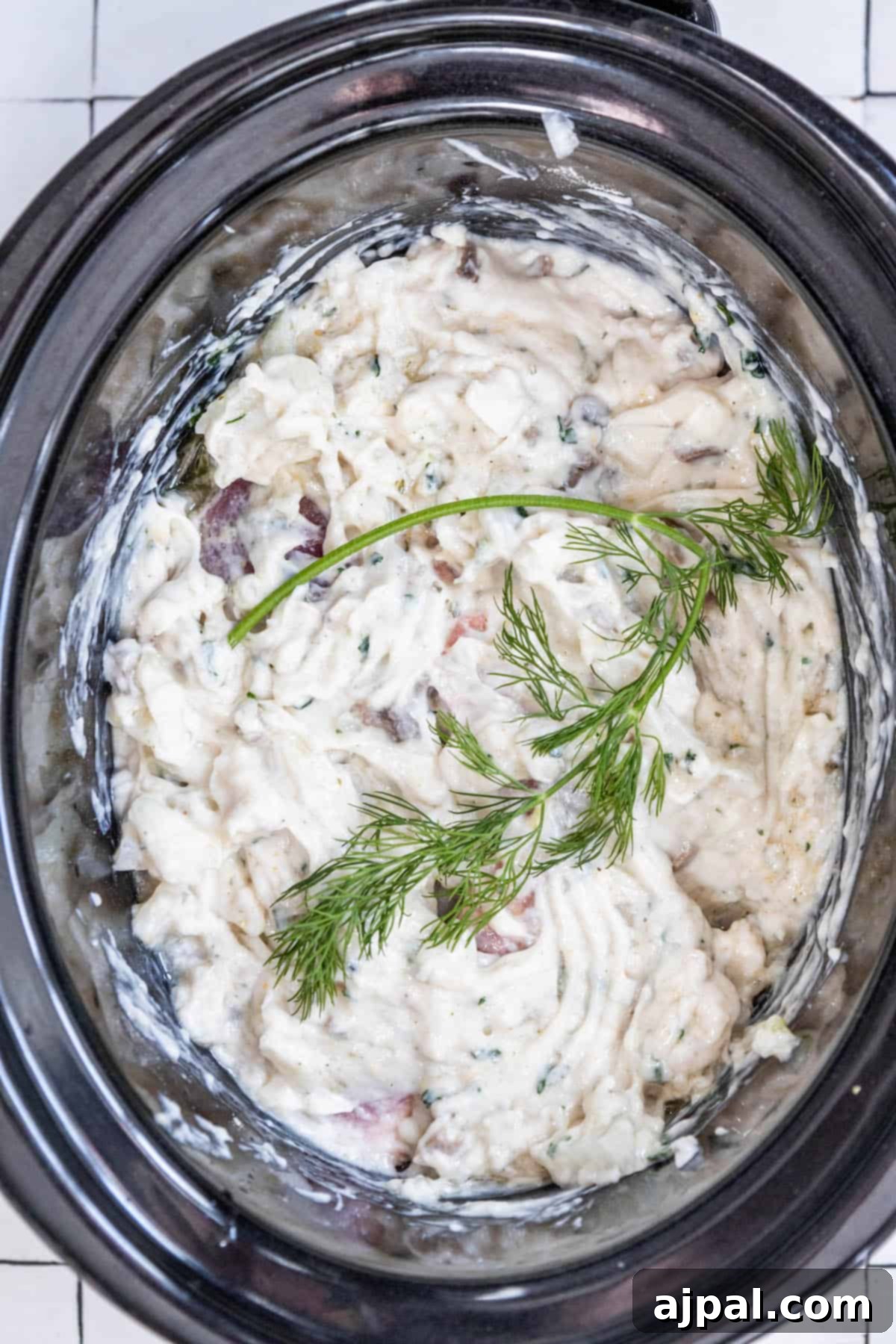 Slow Cooker Creamy Ranch Pork Chops 7 A crock pot filled with creamy mashed potatoes and fresh dill, indicating a side dish.