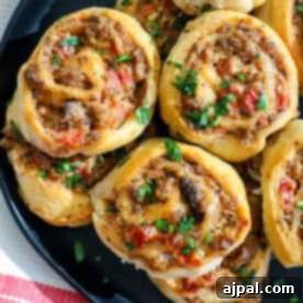 Cheesy meatball rolls on a black plate.