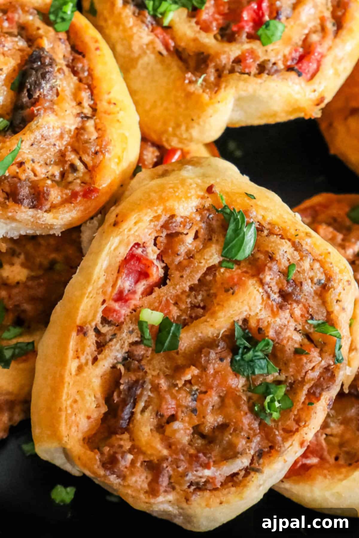 A plate filled with freshly baked sausage pinwheels, garnished with herbs.