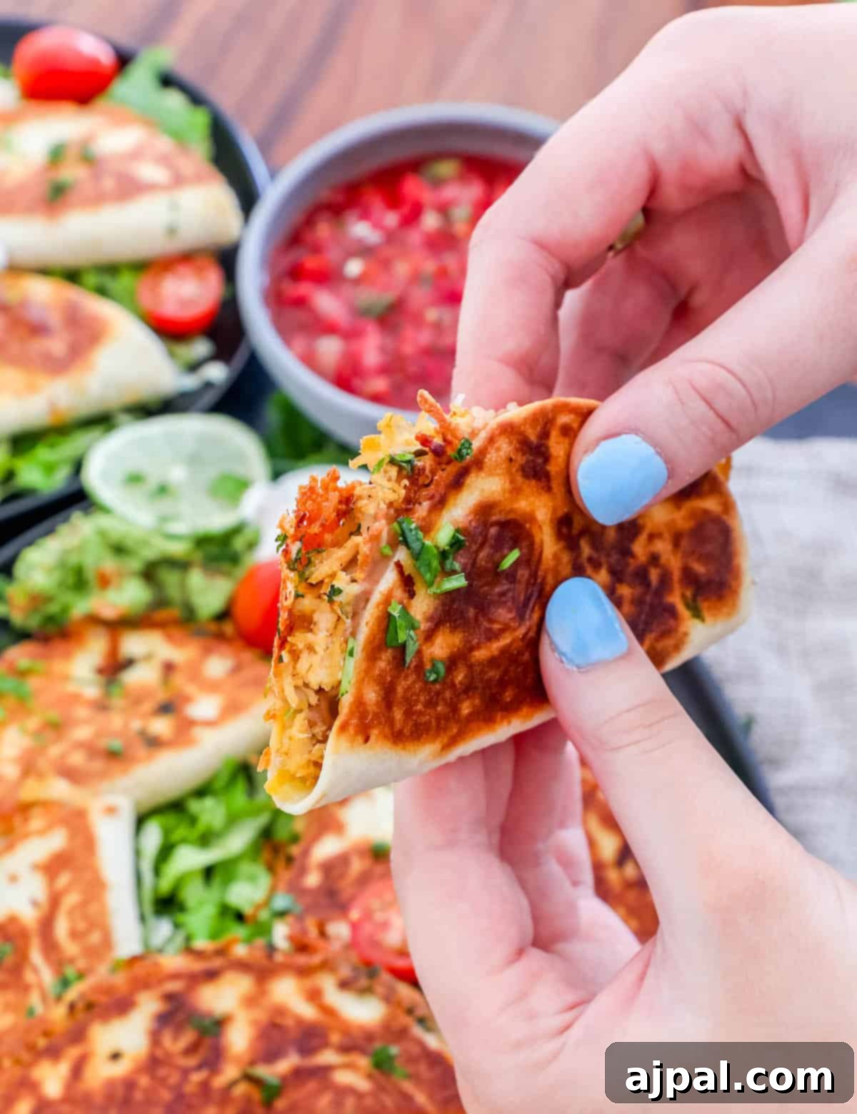 Bite-Sized Chicken Quesadillas 9 A person holding a mini chicken quesadilla on a plate.