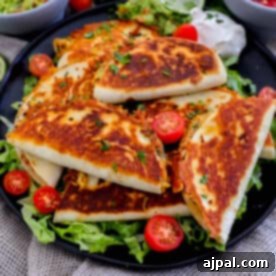 Mini chicken quesadillas on a black plate with tomatoes and guacamole.