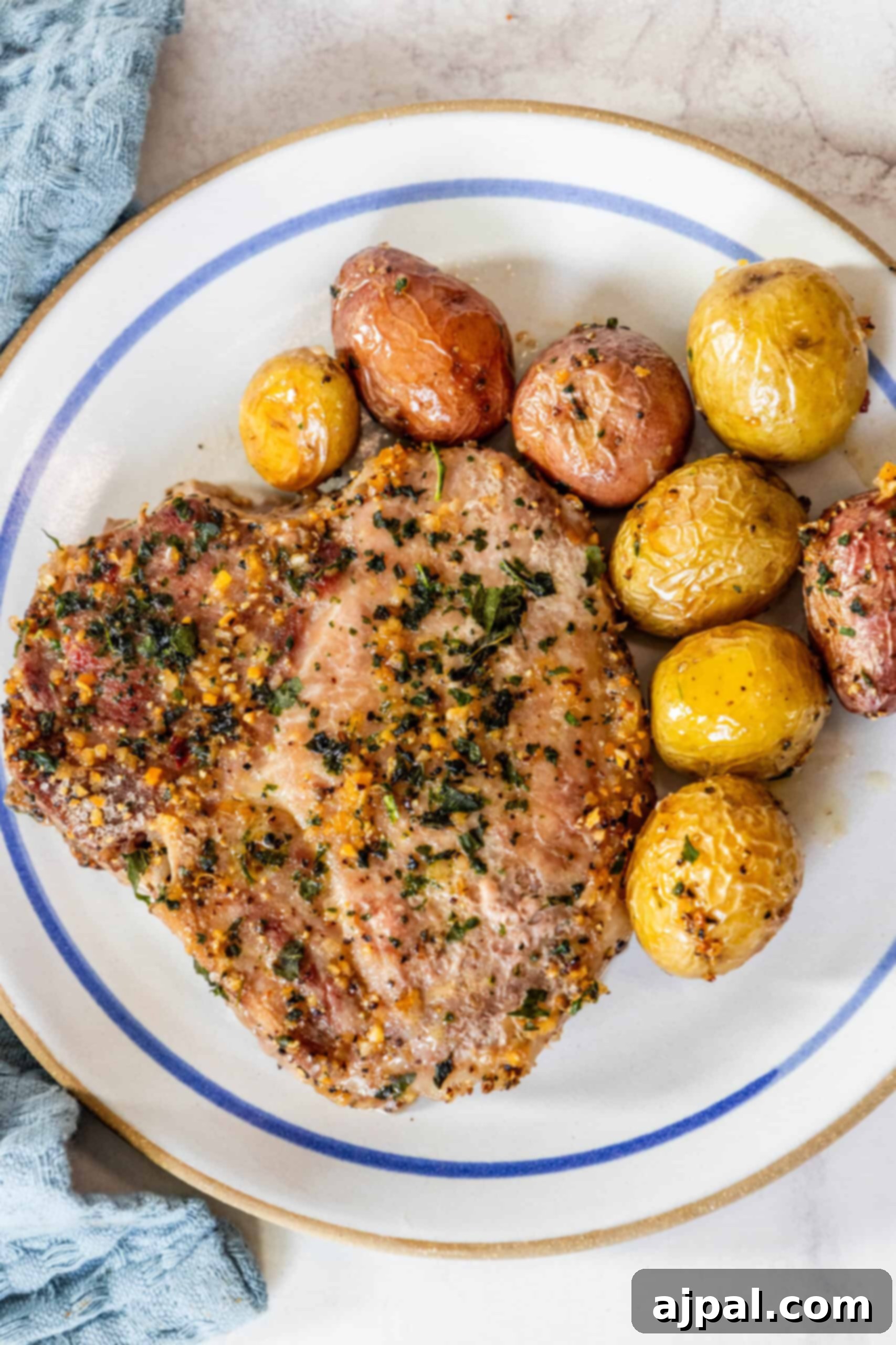 Hearty Pork Chops and Roasted Potatoes 4 A plate of food with potatoes and pork chops. The components are arranged artfully, highlighting the deliciousness of the meal.