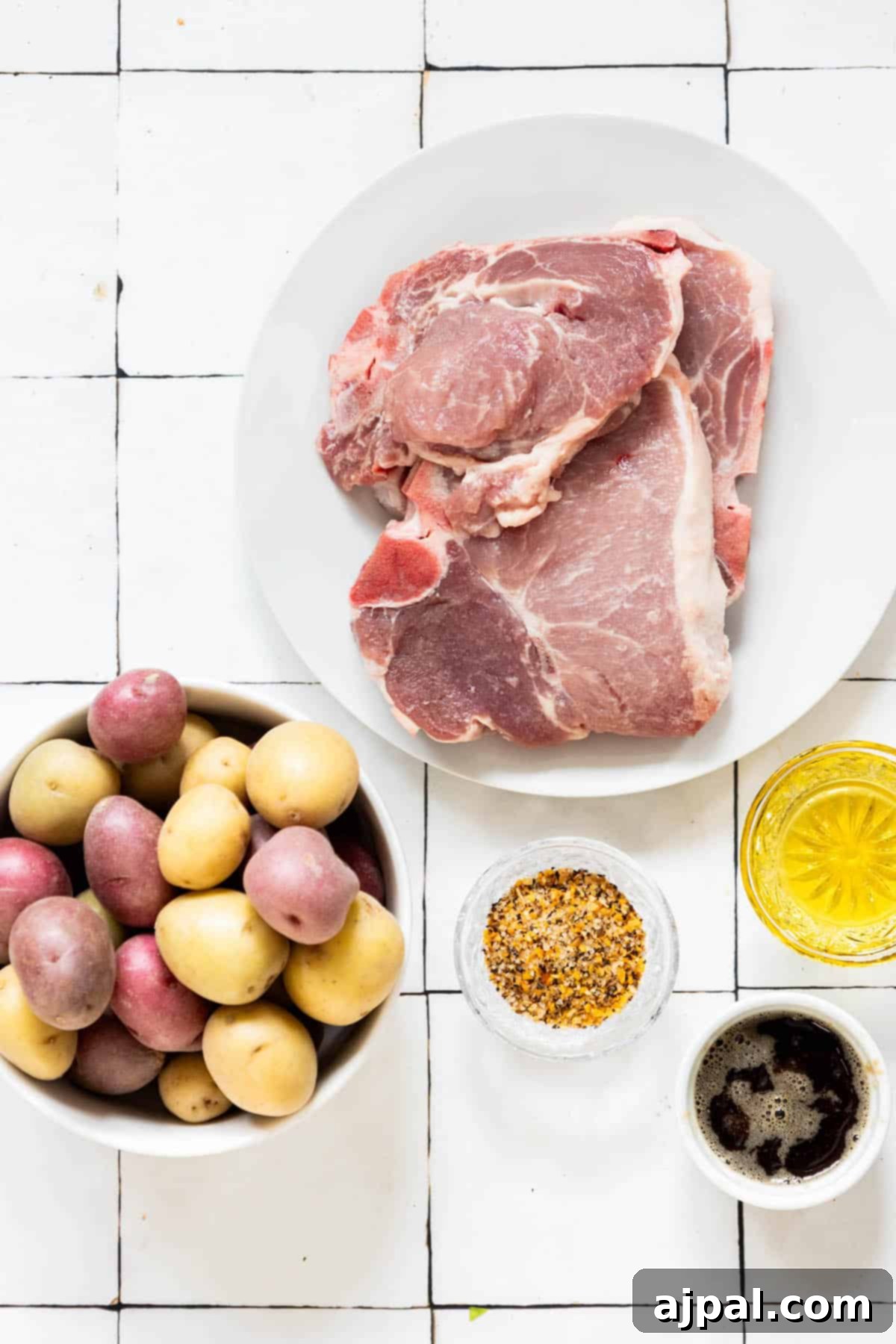 Hearty Pork Chops and Roasted Potatoes 8 A plate of potatoes and pork chops seasoned with spices on a tiled floor.