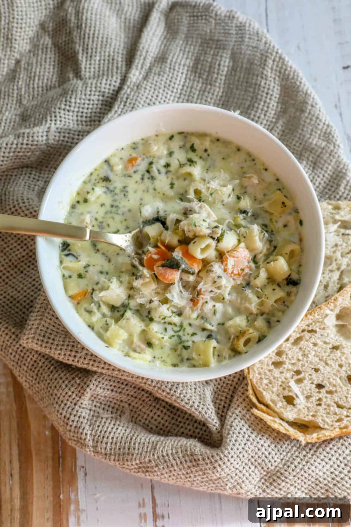 Velvety Creamy Chicken Noodle Soup 2 A creamy bowl of chicken noodle soup with crusty bread on top, ready to be enjoyed.