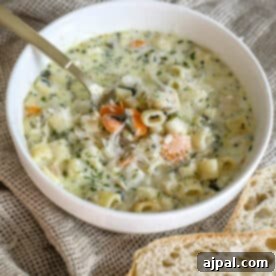 Velvety Creamy Chicken Noodle Soup 9 A creamy bowl of chicken noodle soup with bread next to it, perfect for a cozy meal.