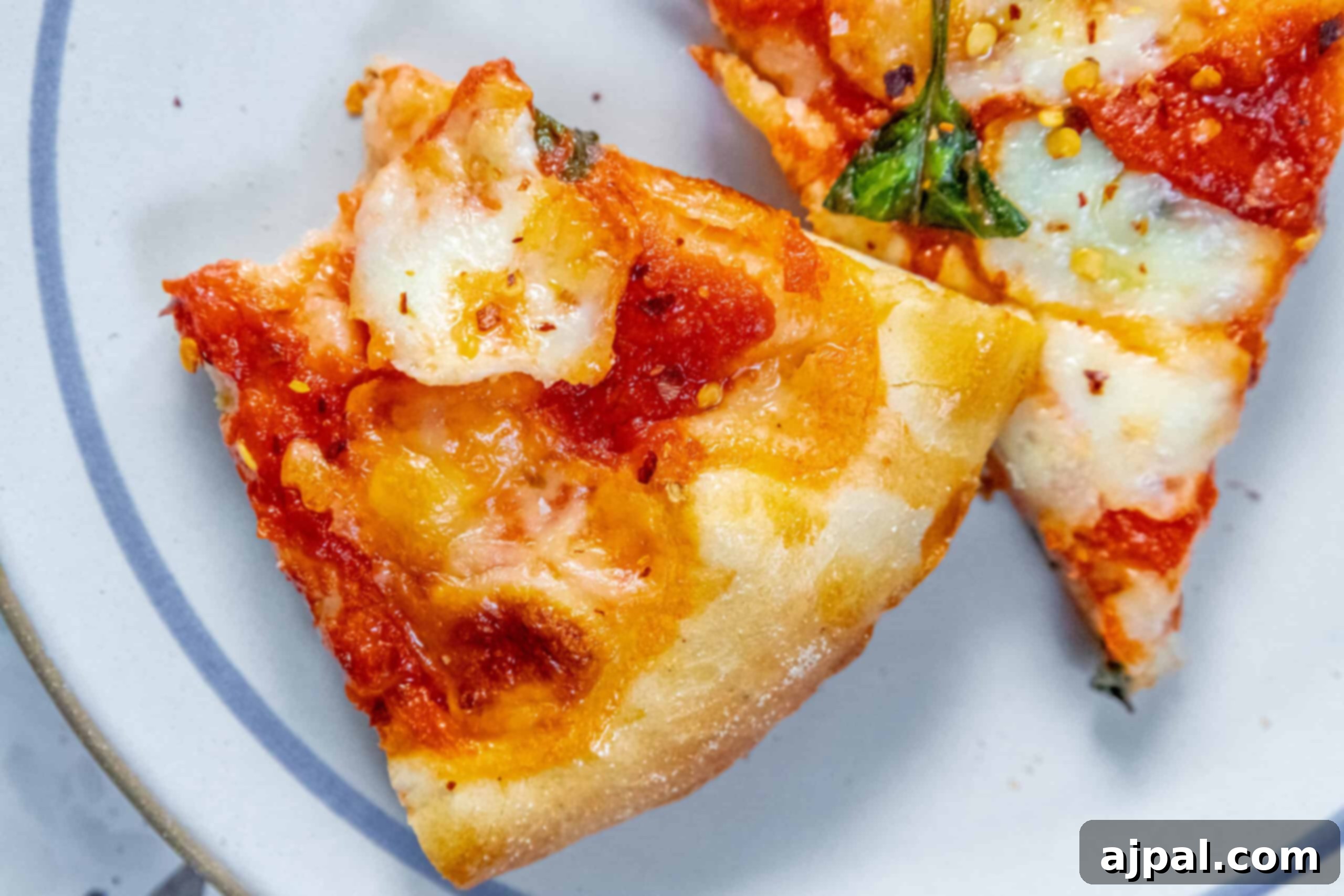 Delicious Margherita Pizza Slices with Homemade Sauce Two enticing slices of Margherita pizza, showcasing the rich sauce and fresh basil, served elegantly on a plate.