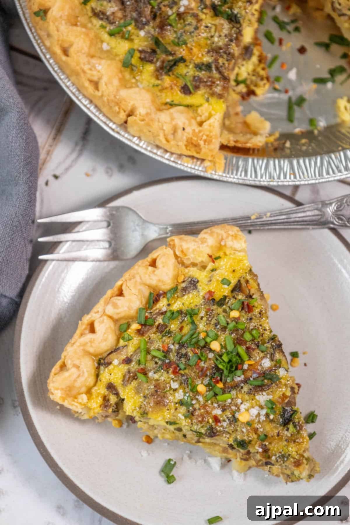 Forest Mushroom Quiche 9 A whole mushroom quiche on a plate with a fork, showing off its golden crust.