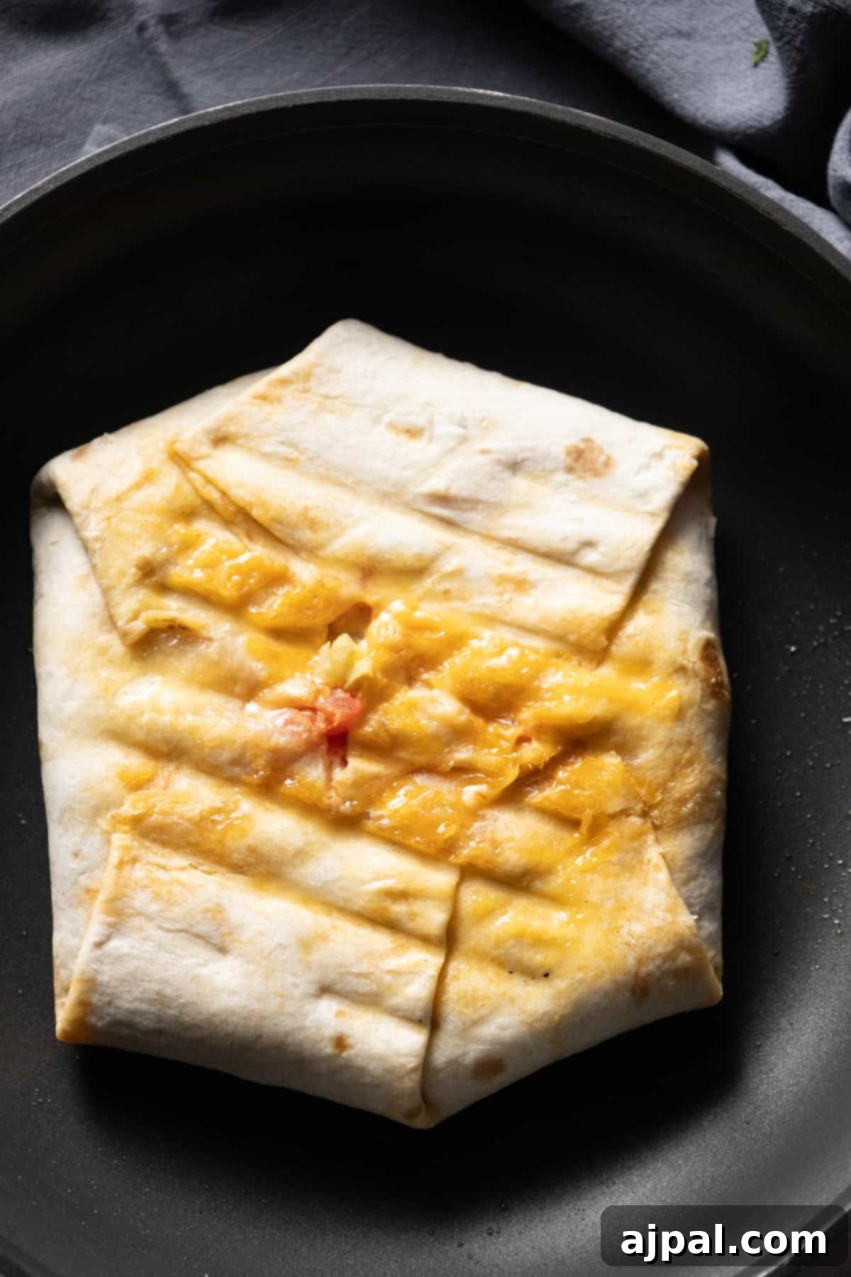 DIY Crunchwrap Delights 11 A crunchy quesadilla with golden, melted cheese sizzling in a frying pan, showcasing the homemade grilling process.