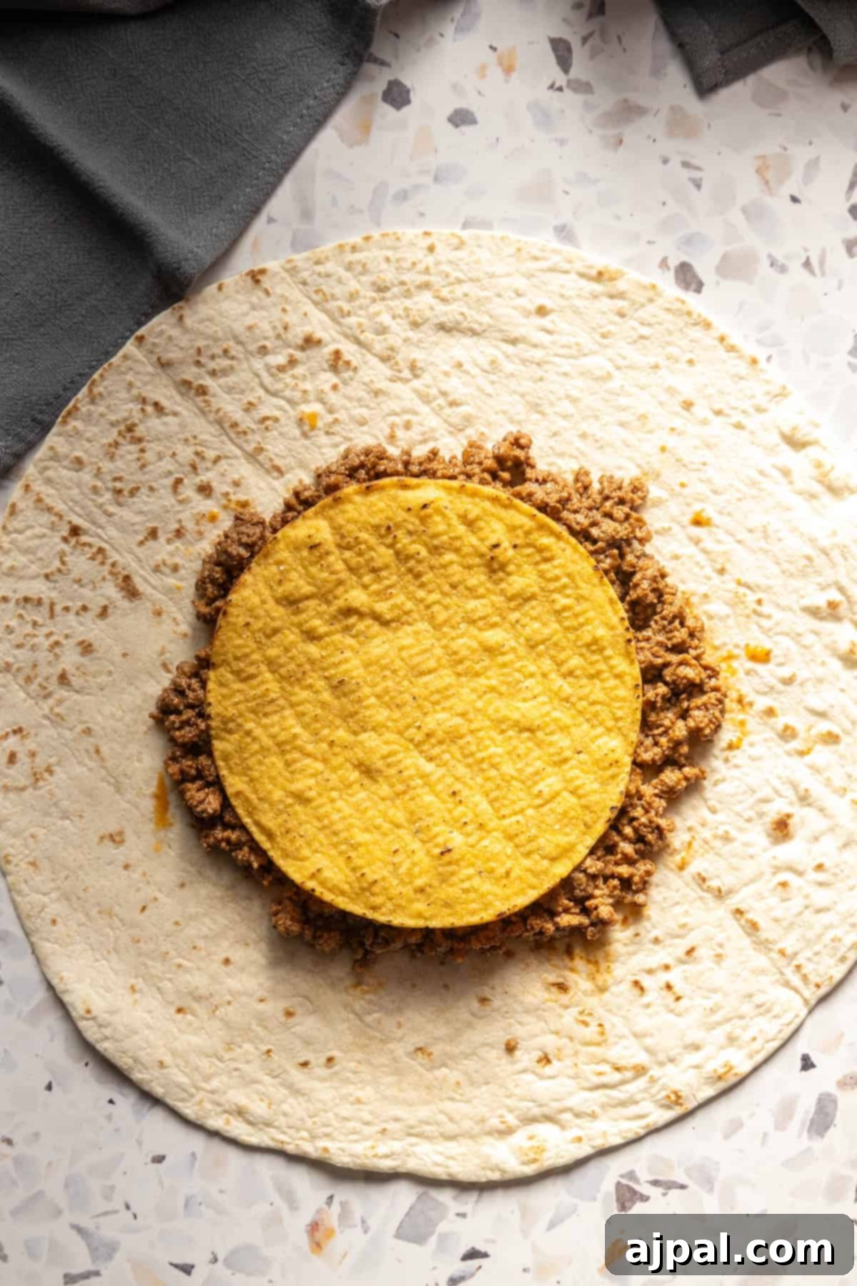DIY Crunchwrap Delights 6 A homemade crunchwrap with a vibrant yellow filling, artfully arranged on a rustic wooden table.