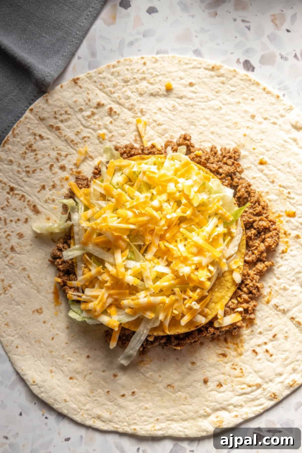 DIY Crunchwrap Delights 7 A generously stuffed homemade burrito, bursting with seasoned meat and melted cheese, ready for grilling.