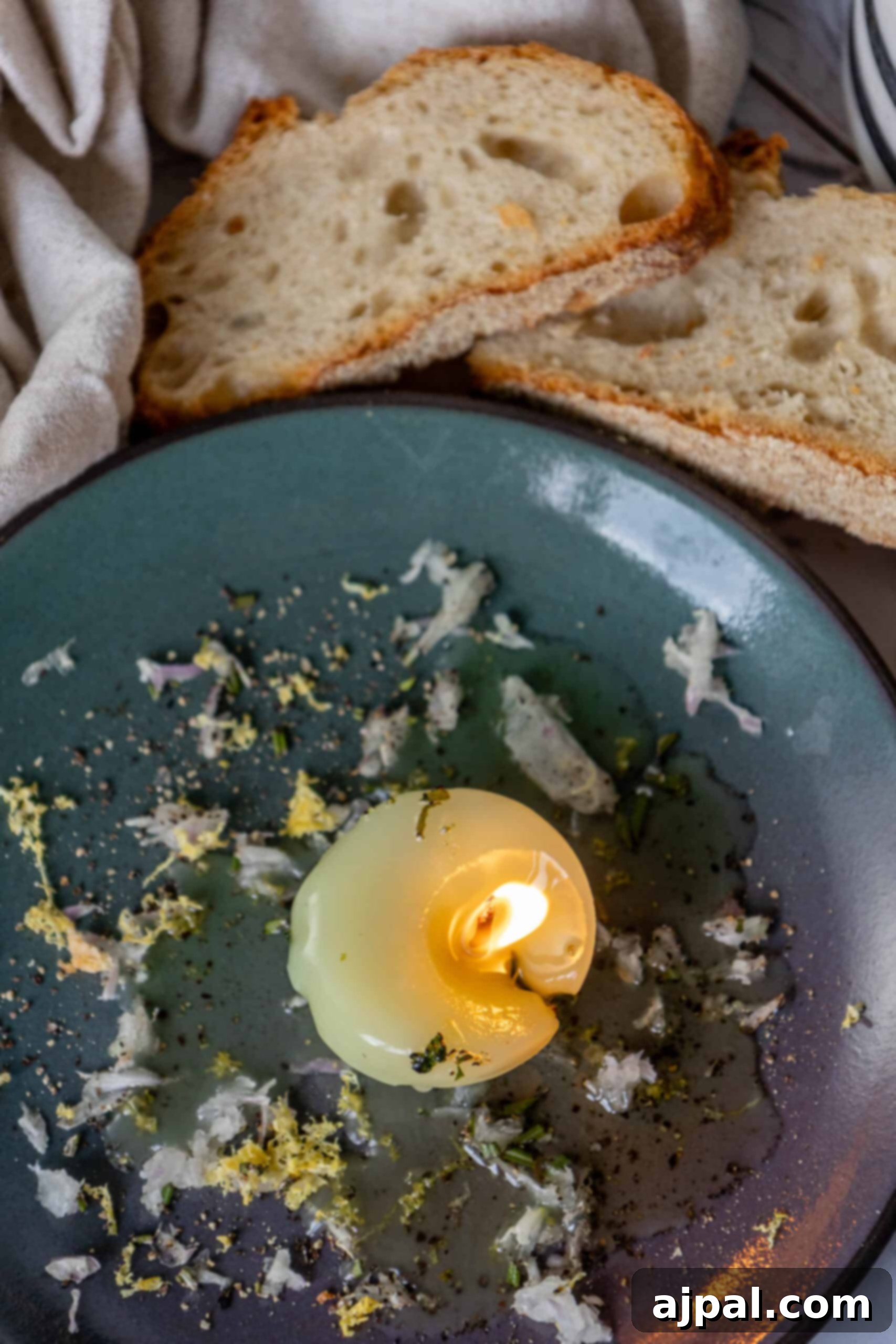 A plate of artisan bread slices with an edible tallow candle melting into a rich dip.