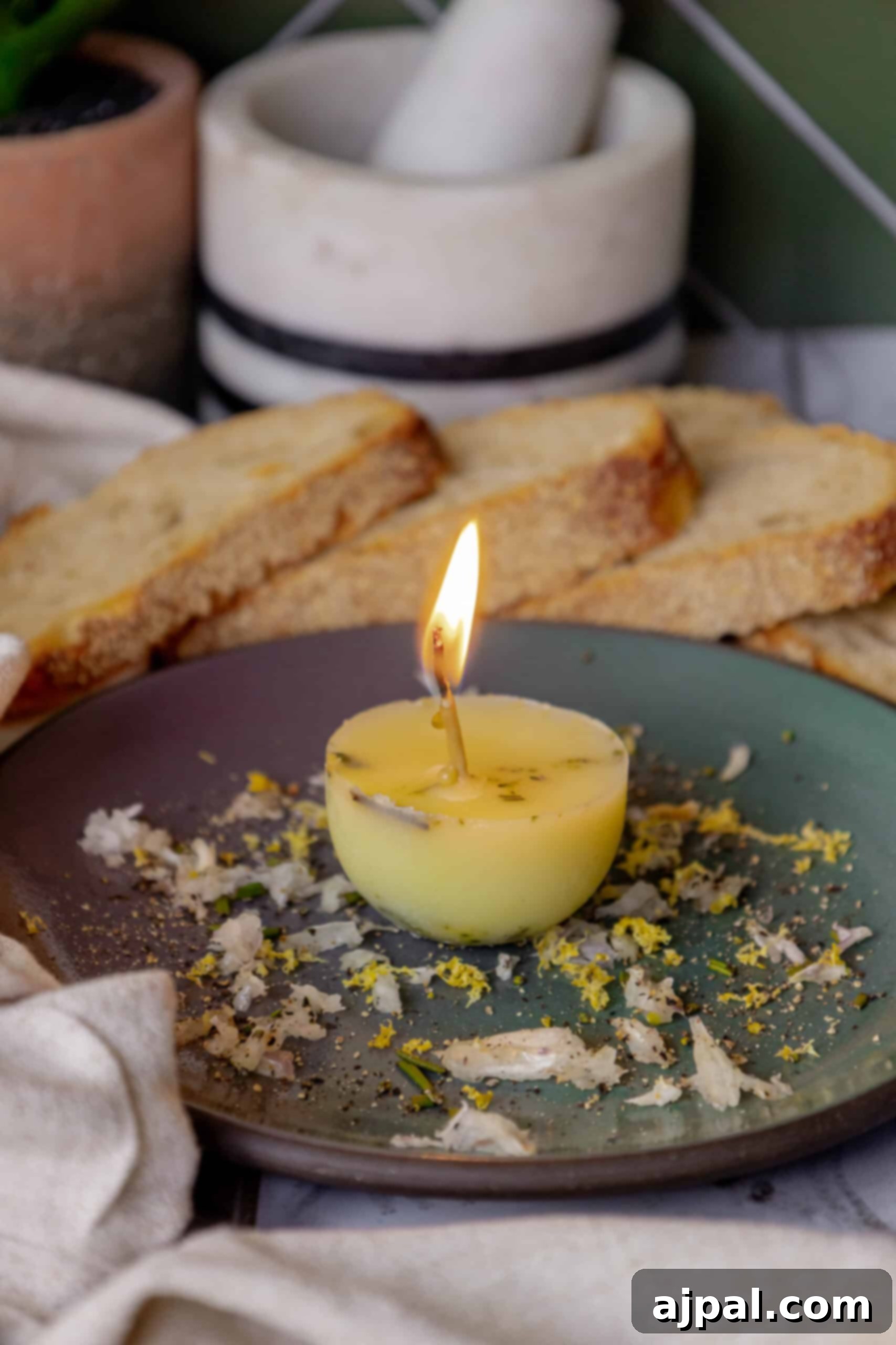 A beautifully presented edible tallow candle resting on a plate alongside freshly baked bread, ready for dipping.